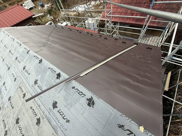 SGL鋼板屋根を軒先側から1枚ずつ丁寧に張り上げている本体施工の様子