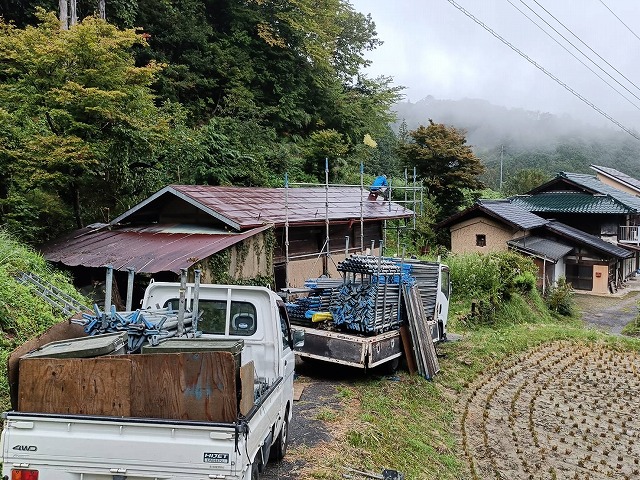 農作業小屋に足場を組み立てている様子と資材を積んだトラック