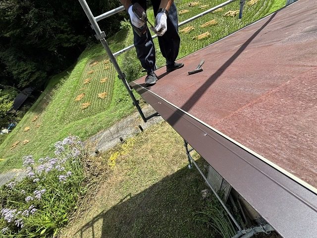 屋根のケラバ部に水切り材をビス留めで取り付ける作業員の様子