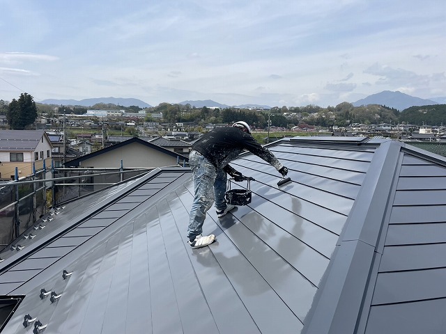 金属屋根塗装工事で「シャネツトップワンSi-JY」による仕上げ塗装を行う屋根職人