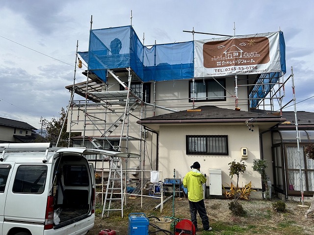 屋根塗装メンテナンスでスレート屋根の上で高圧洗浄を行う屋根職人