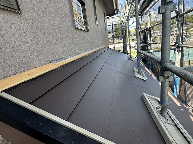 屋根カバー工事で雨押え板金の下地材と外壁との取り合い部へ防水テープの貼り付け