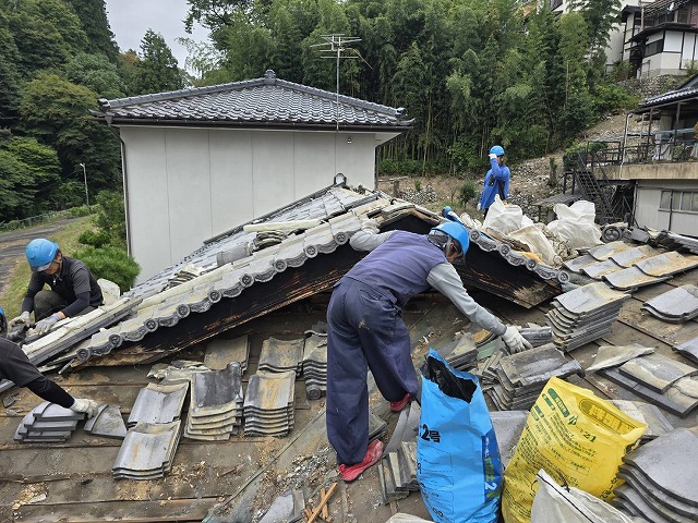 屋根葺き替え工事で既存の瓦材を取り外している屋根職人