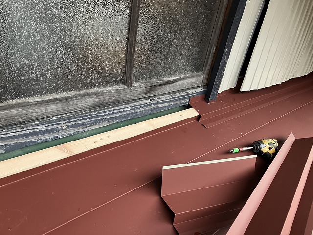 住宅屋根カバー工事の雨押え板金をステンレスビスで固定している様子