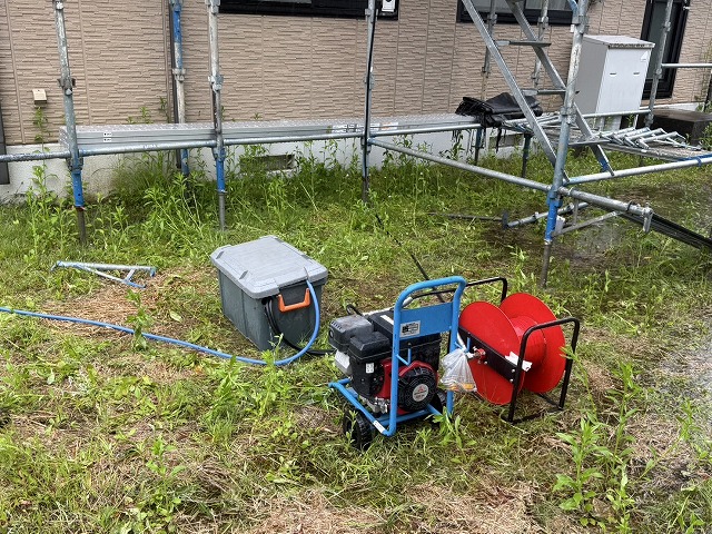 地上にボックスとコンプレッサーを設置して屋根上へ送水しながら高圧洗浄を行っている様子