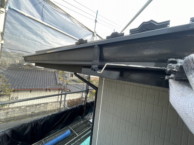 住宅外壁塗装工事の軒樋に対するローラー塗装の様子