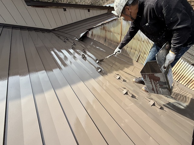 屋根の美観を決める上塗り塗装を塗りムラが出ないよう丁寧に行っている施工の様子