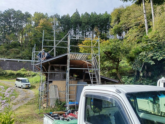 足場が組まれ屋根工事が進む農作業小屋の全景