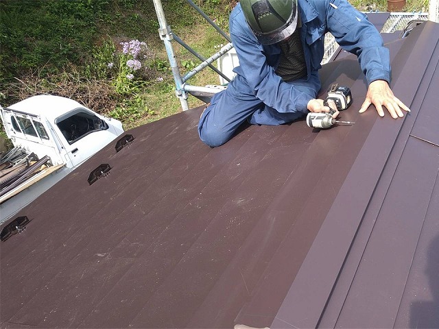 屋根葺き替え・カバー工事で棟板金を下地材に電動ドリルで固定する様子