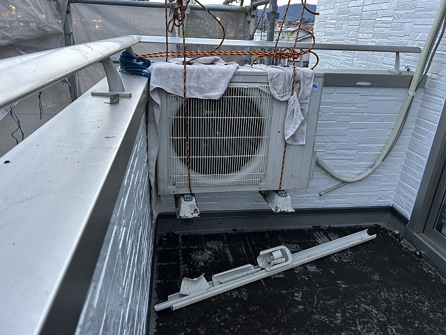 ベランダ防水工事を行う住宅ベランダに設置されていたエアコン室外機の吊り上げ状況