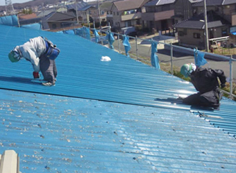 屋根カバー工法で新たな屋根を設置する作業員